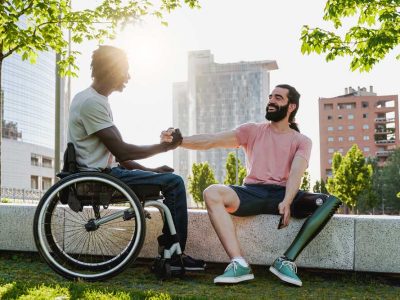 Multiethnic people with disabilities greeting each other outdoor - Focus on right man with leg prosthesis